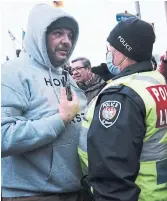  ?? SPENCER PLATT GETTY IMAGES ?? A member of a group supporting the trucker protests argues with police in Ottawa on Friday. The government response to the protests has people feeling abandoned, Althia Raj writes.