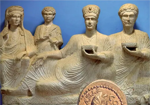  ??  ?? Tesori La scultura che rappresent­a una tipica famiglia di Palmira esposta al museo della città. A fianco una moneta che raffigura Giulio Cesare trovata a Palmira