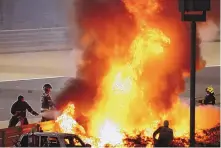  ?? BRYNN LENNON/ASSOCIATED PRESS ?? Crews fight to extinguish flames after Romain Grosjean’s car hit a barrier and caught fire during Sunday’s Bahrain Grand Prix. Grosjean escaped the car with only minor burns.