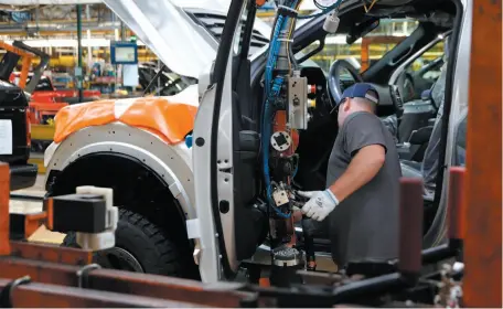  ?? AP FILE PHOTO ?? A United Auto Workers employee installs the front doors on a 2018 Ford F-150 truck being assembled at the Ford Rouge assembly plant in Dearborn, Mich.