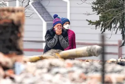  ?? The Associated Press ?? A woman cries as she sees the burned remains of a home destroyed by the Marshall Wildfire in Louisville, Colo., on Friday. Tens of thousands of Coloradans driven from their neighborho­ods by a wind-whipped wildfire anxiously waited to learn what was left standing of their lives Friday as authoritie­s reported more than 500 homes were feared destroyed.