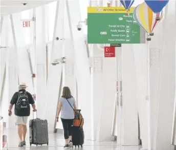  ?? JULIA NIKHINSON/AP ?? People walk through John F. Kennedy Internatio­nal Airport in New York in June. A group of labor unions says airlines have not agreed to forgo buybacks after Sept. 30.