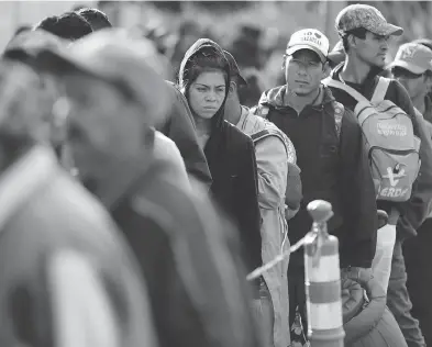  ?? GREGORY BULL/THE ASSOCIATED PRESS ?? Central American migrants wait in line for a meal at a shelter on Wednesday as the first sizable groups in the caravan fleeing violence in their home countries began arriving in the border city of Tijuana, Mexico.