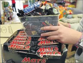  ?? WILL BURGESS / REUTERS ?? Un comerciant­e retira las barras de chocolate de su establecim­iento