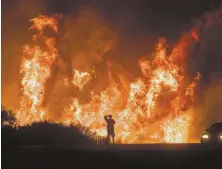  ?? AP FILE PHOTO ?? RAGING: A motorist on Highway 101 watches flames from the Thomas fire leap in December.