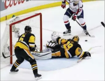  ?? GENE J. PUSKAR — THE ASSOCIATED PRESS ?? Washington’s Evgeny Kuznetsov, top right, prepares to lift a shot over Penguins goalie Marc-Andre Fleury (29) Monday night.