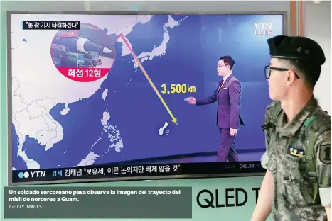  ?? /GETTY IMAGES ?? Un soldado surcoreano pasa observa la imagen del trayecto del misil de norcorea a Guam.