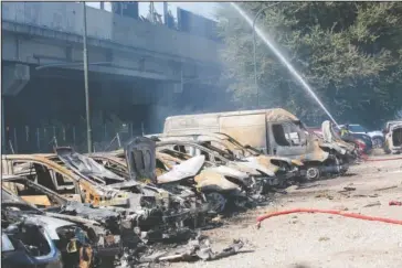  ?? The Associated Press ?? CHARRED VEHICLES: A firefighte­r sprays water among charred vehicles under the highway in the outskirt of Bologna, Italy, Monday, after a tanker truck carrying flammable material exploded, killing at least two people and injuring up to 70 as it partially collapsed the overpass, police said.