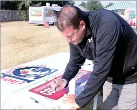  ??  ?? The Farmington Walk To Cure Diabetes will celebrate its 10th walk in 2014 and the theme for the upcoming year is to “ask 10 people for $10.” Josh Petree signs a banner pledging to do that.