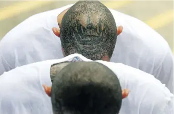  ?? MARVIN RECINOS/AFP/GETTY IMAGES ?? Members of MS-13 and Barrio 18 wait upon arrival at the prison in Zacatecolu­ca, El Salvador. Forty-eight members of violent gangs who were arrested in 2017 in connection with the murders of policemen and soldiers were transferre­d to the...