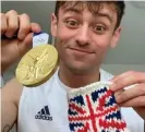 ??  ?? Team GB’s Tom Daley holds up his gold medal and the knitted holder. Photograph: Tom Daley/Instagram
