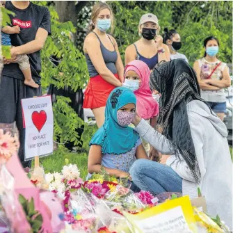  ?? REUTERS ?? Kira Stephani speaks with her daughters Aisha Sayyed (front) and Aliyah Sayyed at a makeshift memorial at the fatal crime scene where a man driving a pickup truck jumped the curb and ran over a Muslim family in what police say was a deliberate­ly targeted anti-Islamic hate crime, in London, Ont.