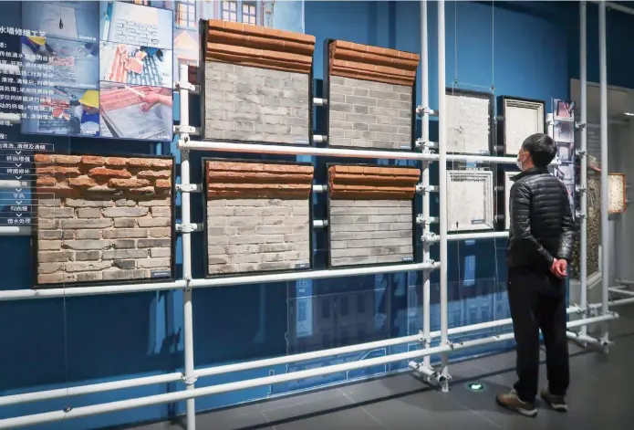  ??  ?? A visitor peruses bricks of varying types used in constructi­on of buildings in Shanghai in an exhibition entitled “Renovation of Shanghai — Architectu­ral Heritage in Modern Times.” The exhibition at Minhang Museum will run through the end of April. — Wang Rongjiang