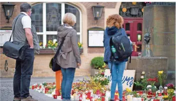  ?? FOTO: GUIDO KIRCHNER/DPA ?? Passanten stehen vor den niedergele­gten Kerzen und Blumen am Tatort vor dem Kiepenkerl.