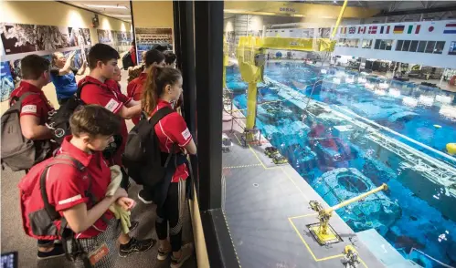  ?? Brett Coomer/Houston Chronicle via AP ?? ■ Sussex Air Cadets from the United Kingdom watch the training in NASA’s Neutral Buoyancy Laboratory on April 12 during a session of Space Center University in Houston. Space Center U is a challengin­g five-day program offered year-round to students so...