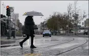  ?? JEFF CHIU — THE ASSOCIATED PRESS ?? A pedestrian carries an umbrella while crossing a street at Fisherman’s Wharf in San Francisco on Wednesday.