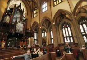  ?? KATHY WILLENS—THE ASSOCIATED PRESS ?? In this May 2, 2018, photo, tourists pause to snap photograph­s from a pew at Trinity Church in New York. Trinity’s nave with its 66-foot vaulted ceiling will be off limits during the $98 million renovation that starts Monday, but a small chapel at the...