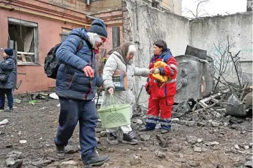  ?? (AFP) ?? Women, one wounded, leave their partially destroyed residentia­l following a Russian missile strike in Kharkiv, on Sunday