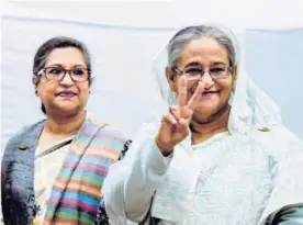  ?? AFP ?? La primera ministra de Bangladés, Sheikh Hasina (der.), saluda después de emitir su voto en una mesa electoral en la ciudad de Daca.