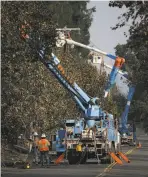  ?? Elijah Nouvelage / Getty Images ?? PG&E workers repair power lines in Santa Rosa’s Coffey Park.