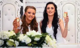  ??  ?? Robyn Peoples (left) and Sharni Edwards make a toast during their wedding in Loughshore hotel in Carrickfer­gus. Photograph: Mark Marlow/EPA