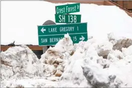  ?? Gina Ferazzi Los Angeles Times ?? STREET SIGNS stick out above piles of snow plowed from roads off Highway 138 in the San Bernardino Mountains community of Crestline on Monday.