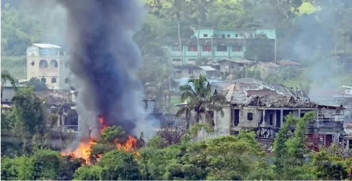  ?? AFP ?? Smoke billows from burning houses after Philippine Airforce attack planes conducted aerial bombings on militants’ positions in Marawi on Monday. —