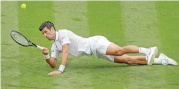  ?? | AFP ?? SERBIA’S Novak Djokovic slips on the grass as he plays a return against Britain’s Jack Draper in their first round encounter at Wimbledon yesterday.