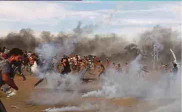  ?? REUTERS PIC ?? Palestinia­ns running from tear gas fired by Israeli troops during a protest in Gaza on Friday.