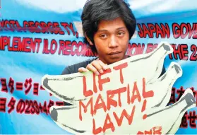  ?? AP FOTO ?? NO TO EXTENSION. A protester holds a placard to protest the proposed extension until December 31 this year of martial law and suspension of the writ of habeas corpus in Mindanao.