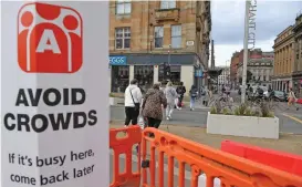  ?? (AFP) ?? A sign alerts pedestrian­s and shoppers to ‘Avoid Crowds’ due to COVID-19 in Glasgow on April 26