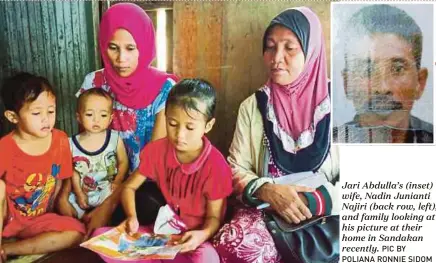  ?? PIC BY POLIANA RONNIE SIDOM ?? Jari Abdulla’s (inset) wife, Nadin Junianti Najiri (back row, left), and family looking at his picture at their home in Sandakan recently.