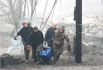  ??  ?? Yuba and Butte County sheriff deputies carry a body bag with a deceased victim of the Camp Fire in Paradise.— AFP photo