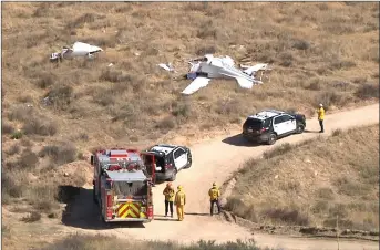  ?? Austin Dave/The
Signal ?? Emergency response crews assess a plane crash in Agua Dulce on Sunday. Four people were killed in the crash after a Cirrus VK-30 collided with a hillside south of Highway 14. The victims were family members.