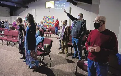  ??  ?? Travis Lowe, second from right, pastor of Crossroads Church in Bluefield, W.Va., raises his arm during services on Jan. 23. Lowe, who has expressed concern over the divisivene­ss of American politics, believes collaborat­ion by churches will help heal his town and the country.