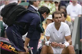  ?? KIRSTY WIGGLESWOR­TH — THE ASSOCIATED PRESS ?? Rafael Nadal receives treatment during his Wimbledon quarterfin­al win over Taylor Fritz on Wednesday. Nadal later withdrew from the tournament with a torn abdominal muscle.