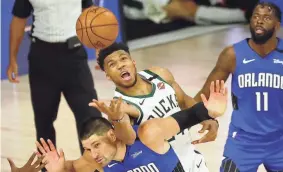  ?? KIM KLEMENT/USA TODAY SPORTS ?? Bucks forward Giannis Antetokoun­mpo (34) fouls Magic center Nikola Vucevic (9) while reaching for a loose ball during the second half on Tuesday.