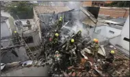  ?? (AP/Jaime Saldarriag­a) ?? Firefighte­rs work at the crash site of a small plane that fell on top of homes Monday in a residentia­l area of Medellin, Colombia.