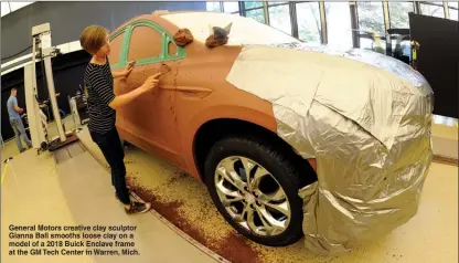 ?? The Associated Press ?? General Motors creative clay sculptor Gianna Ball smooths loose clay on a model of a 2018 Buick Enclave frame at the GM Tech Center in Warren, Mich.