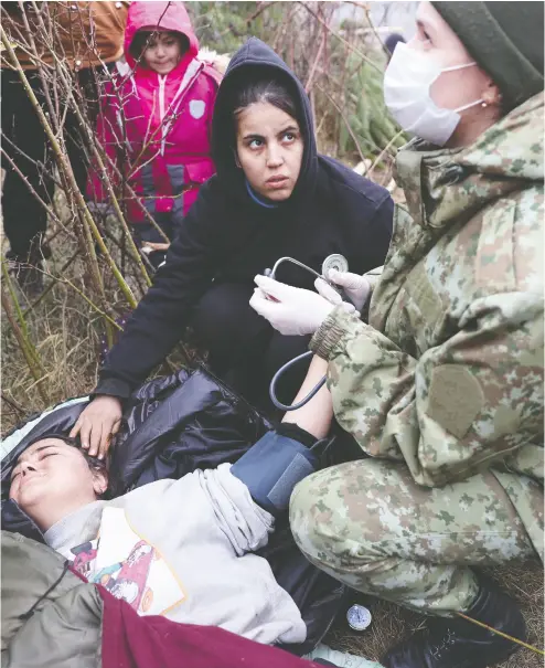  ?? RAMIL NASIBULIN / BELTA / AFP VIA GETTY IMAGES ?? A migrant receives medical attention on the Belarusian-polish border Thursday. Hundreds of desperate migrants are
trapped on the border as part of a wave the EU says is orchestrat­ed by Belarusian president Alexander Lukashenko.