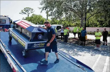  ?? MEGHAN MCCARTHY / THE PALM BEACH POST ?? Zuccala Towing employee Jose Oquendo loads a symbolic casket onto a tow truck bound for Pompano Beach on Friday, part of The Spirit Ride campaign to raise awareness of “Slow Down, Move Over” laws.