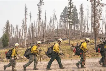  ?? Nathan Howard / Associated Press ?? Firefighte­rs from New Mexico walk toward the northwest edge of the Bootleg Fire while working to build a containmen­t line near Paisley, Ore. Less than half of it has been contained.