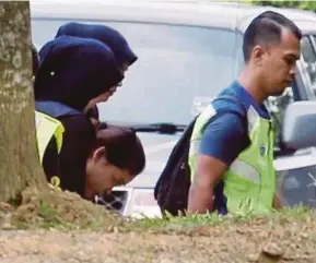  ??  ?? Police officers escorting Siti Aisyah (head bowed) to the Sepang Court Complex yesterday.