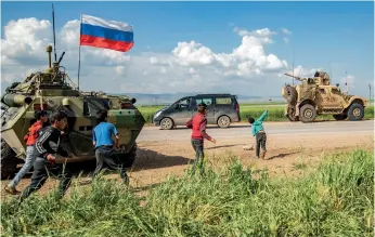  ??  ?? Cachés derrière un char russe, des enfants jettent des pierres sur un véhicule américain à Tannuriyah, près de Qamichli, en mai 2020.