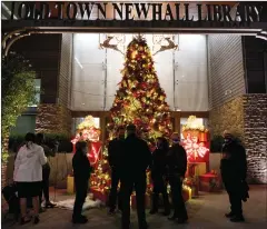  ?? Shae Hammond/ For The Signal ?? (Above) City Council members gather around the Christmas tree after turning on the lights during the virtual Light Up Main Street ceremony in Newhall on Thursday. (Below) Ahead of the lighting ceremony, a woman takes a photo of a stuffed reindeer in front of the tree outside the Old Town Newhall Library.