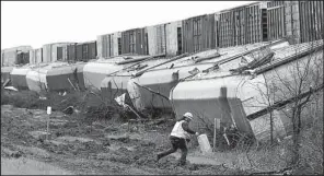  ?? AP/Austin American-Statesman/RALPH BARRERA ?? A worker walks near a train that derailed early Monday in Thrall, Texas, after severe storms moved through area.