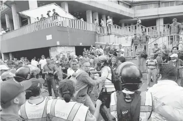  ??  ?? Police intervene to stop a fight between Venezuelan opposition activists and supporters of Maduro outside of the Santa Therese church in Caracas during the celebratio­n of the Nazarene of San Paul Christ’s day as part of the commemorat­ions for the Holy...