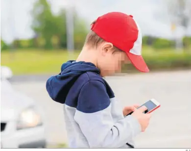  ?? M. G. ?? Un niño manipula un teléfono móvil en la calle.