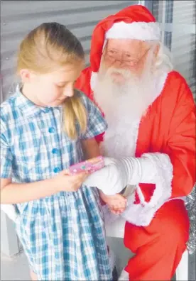  ?? SUPPLIED ?? Hastings RDA rider Olivia MacGregors happily accepts a gift from volunteer and Santa Trevor Bixley.