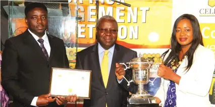  ?? — (Picture by Kudakwashe Hunda) ?? Energy and Power Developmen­t Permanent Secretary Mr Partson Mbiriri (centre) poses for a photograph after handing over a trophy to the overall winner in the Substation­s Risk Compliance category ZETDC health safety officer Florida Mutomba (right) and a...